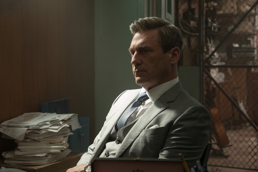 Jon Hamm, as Coop, is sitting in a pawn shop's back office, looking somber.