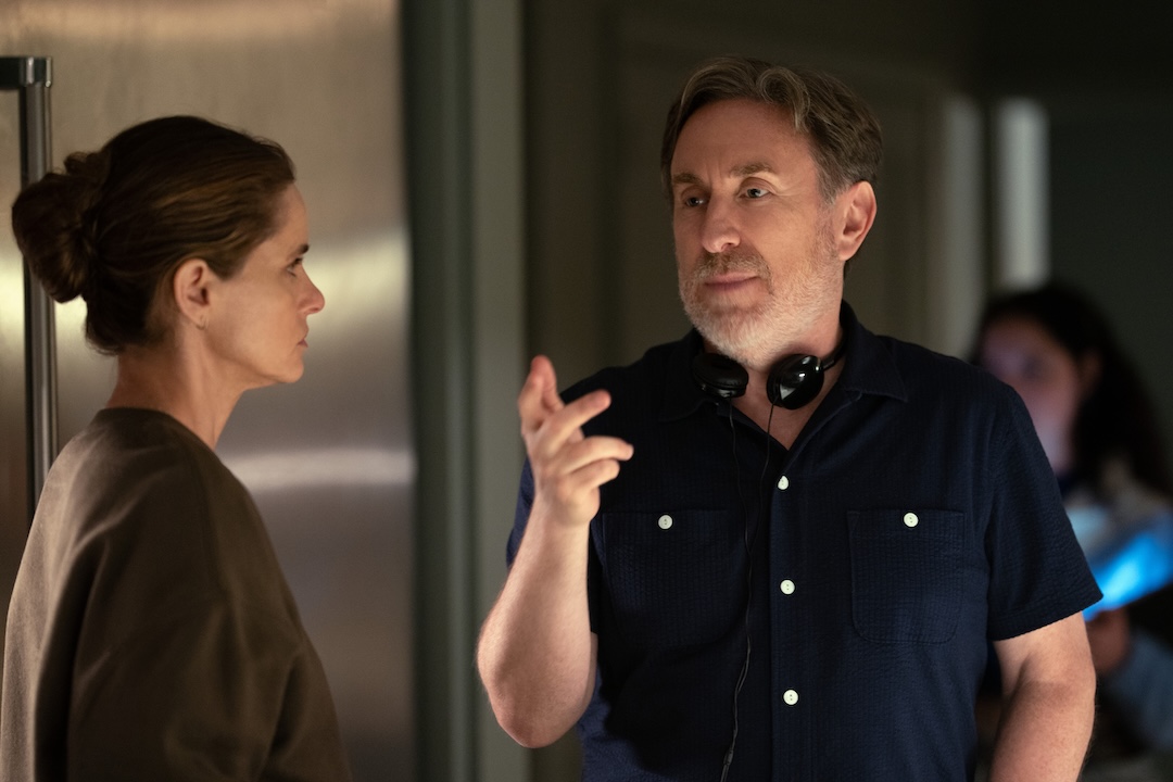 Jonathan Tropper, wearing headphones around his neck, speaks with Amanda Peet on set